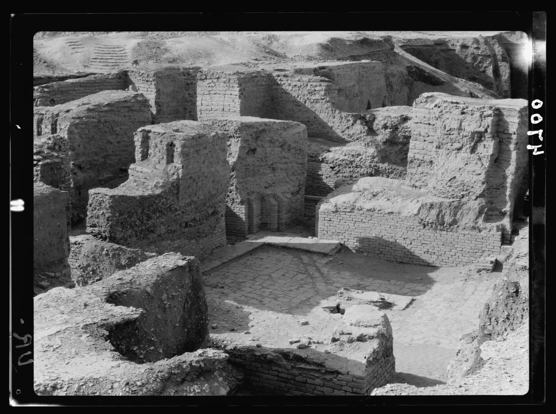 Archival black-and-white photograph of excavated brick rooms and a paved courtyard at Ur.