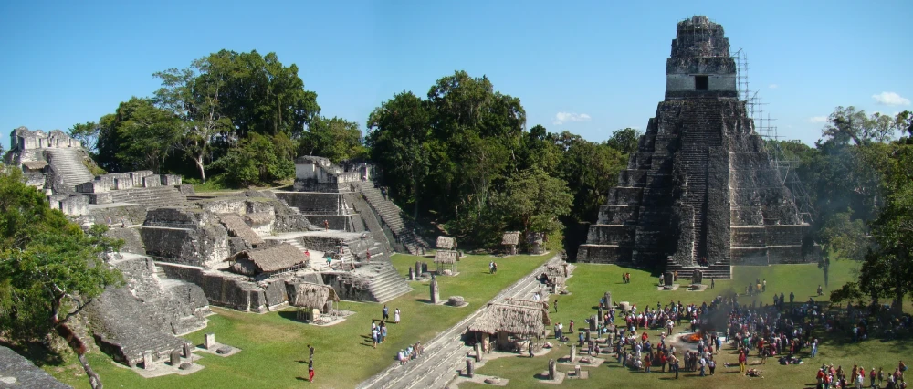 Temple I and stepped structures around Tikal’s Great Plaza, with trees and visitors below.