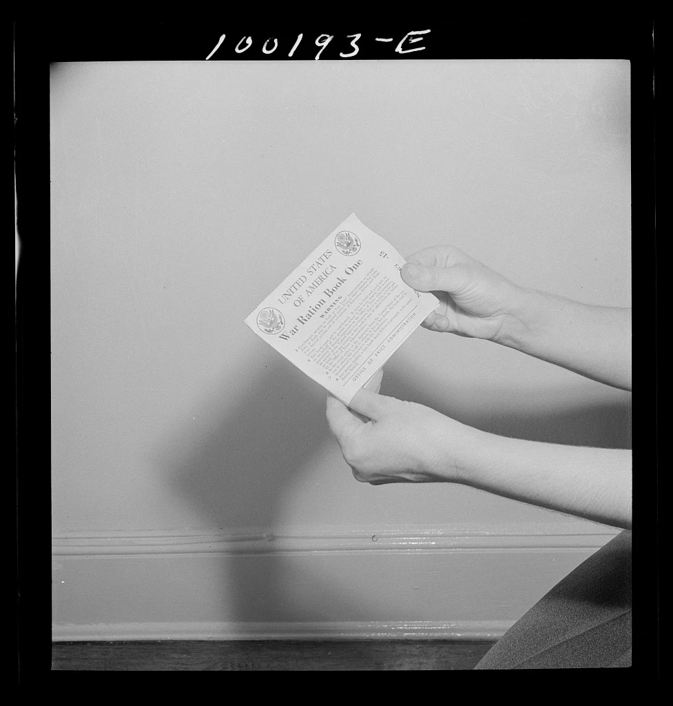 Two hands hold the front cover of a US War Ration Book One.
